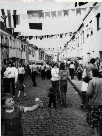 eine Straße mit Kopfsteinpflaster, Erwachsenen und spielenden Kindern 